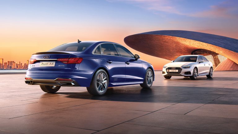 Two Audi A4 sedans showcased beside a futuristic architectural structure at sunset, highlighting elegant styling