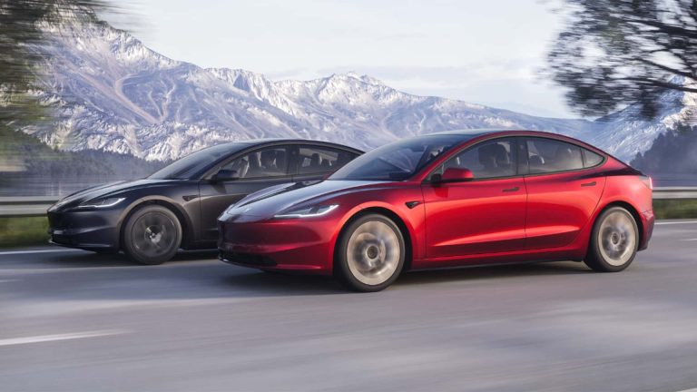 Two Tesla Model 3 sedans drive along a scenic highway beneath snow-capped mountains
