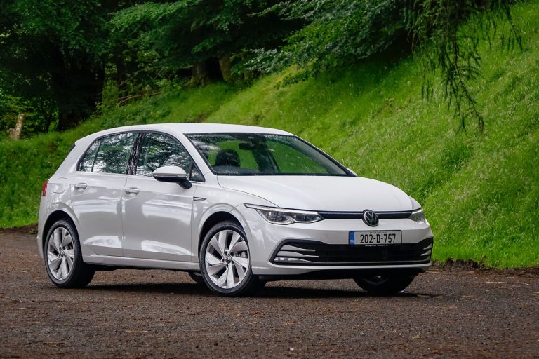 Volkswagen Golf TDI parked beside a lush green hillside on a quiet road