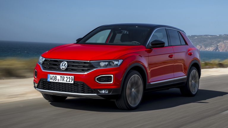 Volkswagen T-Roc cruising along a coastal road, highlighting its sporty crossover styling and dynamic design