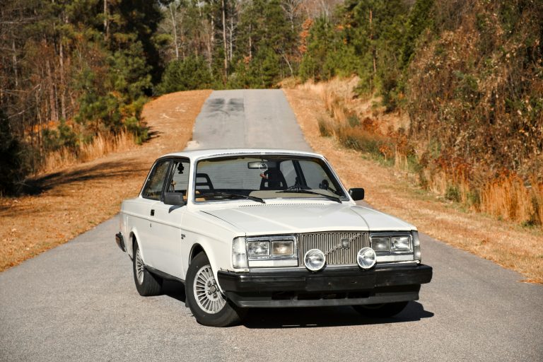 A VOLVO 240 i standing in the middle of a road on a sunny day