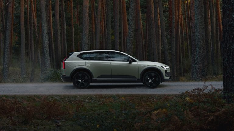Volvo EX60 P10 AWD electric SUV parked beside a dense forest, showcasing its sleek Scandinavian design