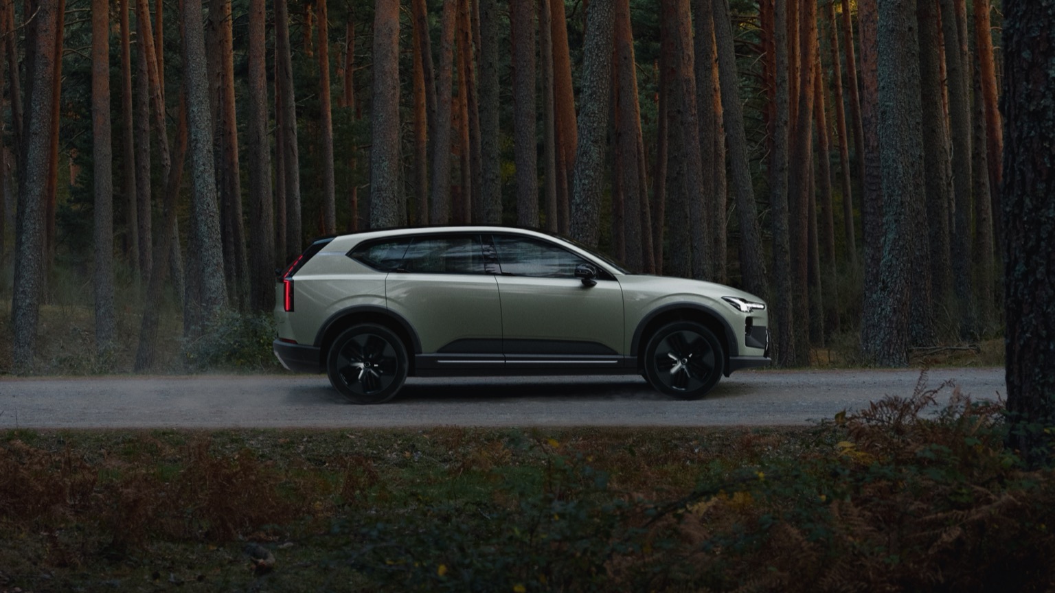 Volvo EX60 P10 AWD electric SUV parked beside a dense forest, showcasing its sleek Scandinavian design