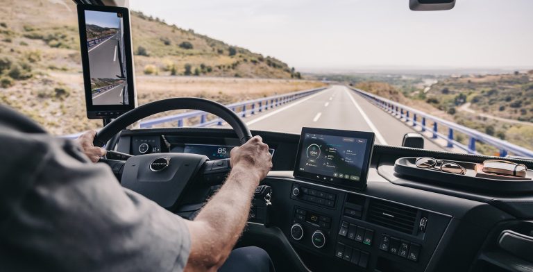 Volvo truck driver using a digital dashboard and camera-monitor system while traveling along an open highway