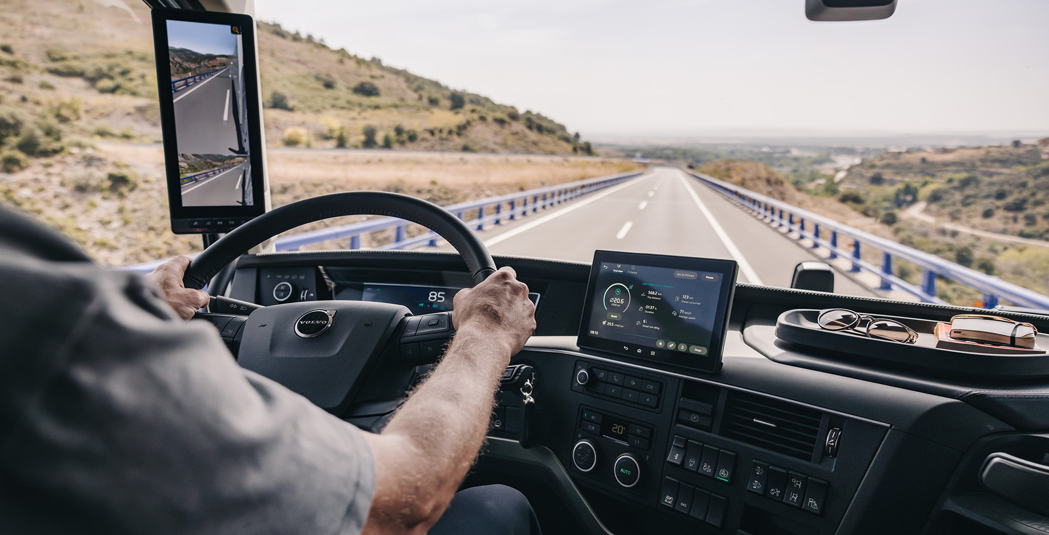 Volvo truck driver using a digital dashboard and camera-monitor system while traveling along an open highway