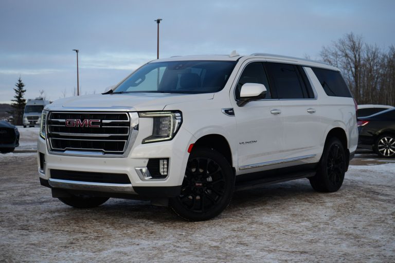 White GMC Yukon XL parked in a snowy lot, showcasing its spacious body and bold front grille