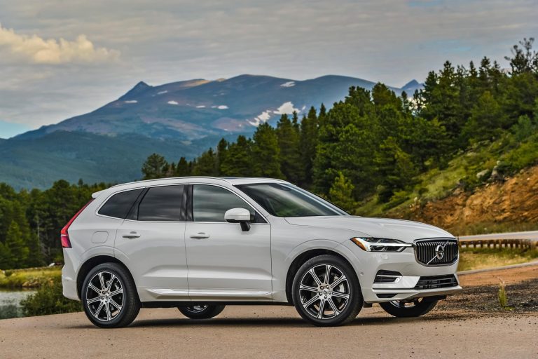 White Volvo XC60 parked beside a scenic mountain road, showcasing its elegant Scandinavian SUV design