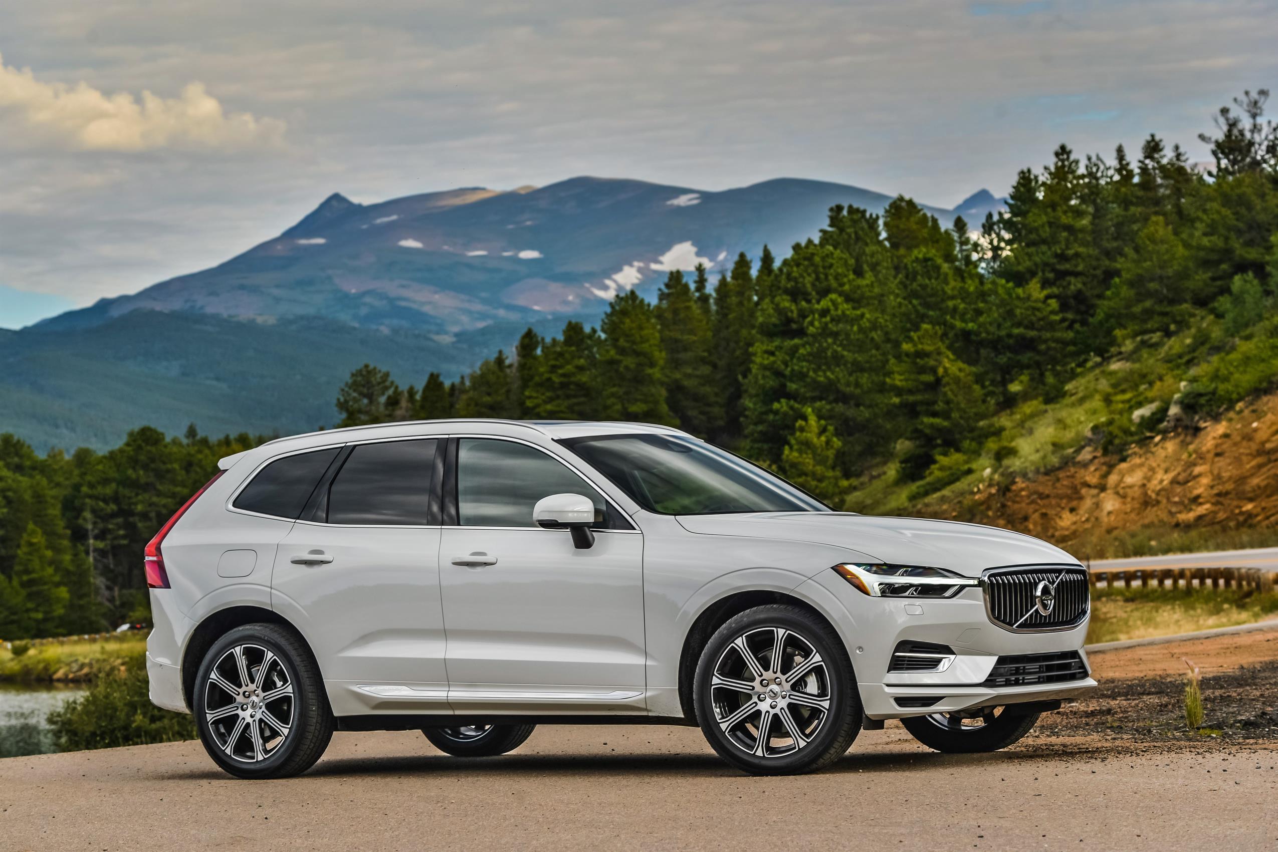 White Volvo XC60 parked beside a scenic mountain road, showcasing its elegant Scandinavian SUV design