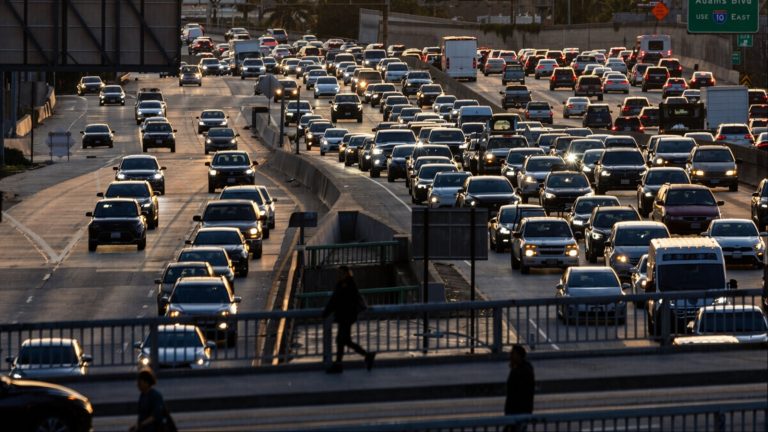 Dense traffic congestion on multi-lane highway at sunset with pedestrians