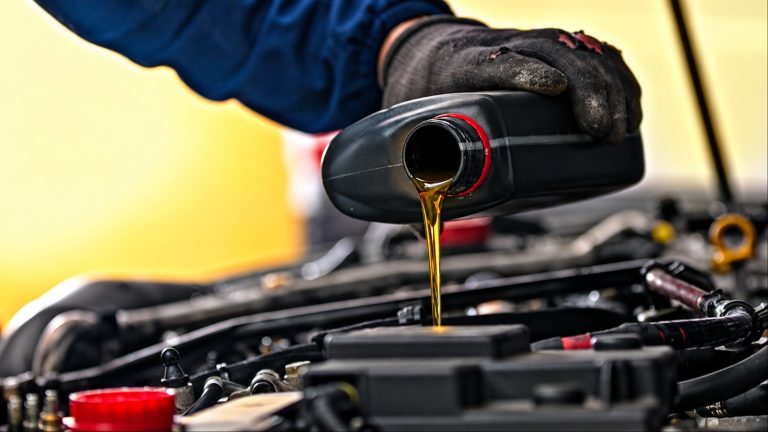 Mechanic pouring fresh motor oil into a vehicle engine during a routine oil change service in a professional repair shop