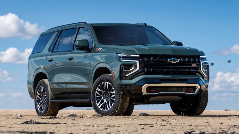Chevrolet Suburban sits on a sandy beach with rugged terrain behind