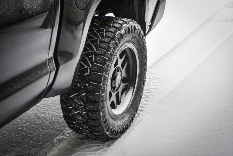 A car in winter snow is shown where the tires are wrapped in winter snow