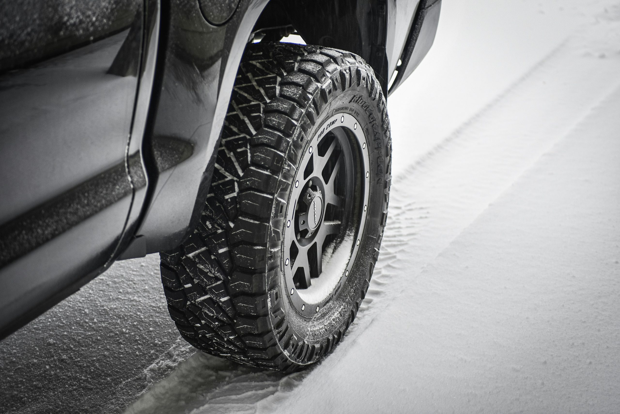 A car in winter snow is shown where the tires are wrapped in winter snow
