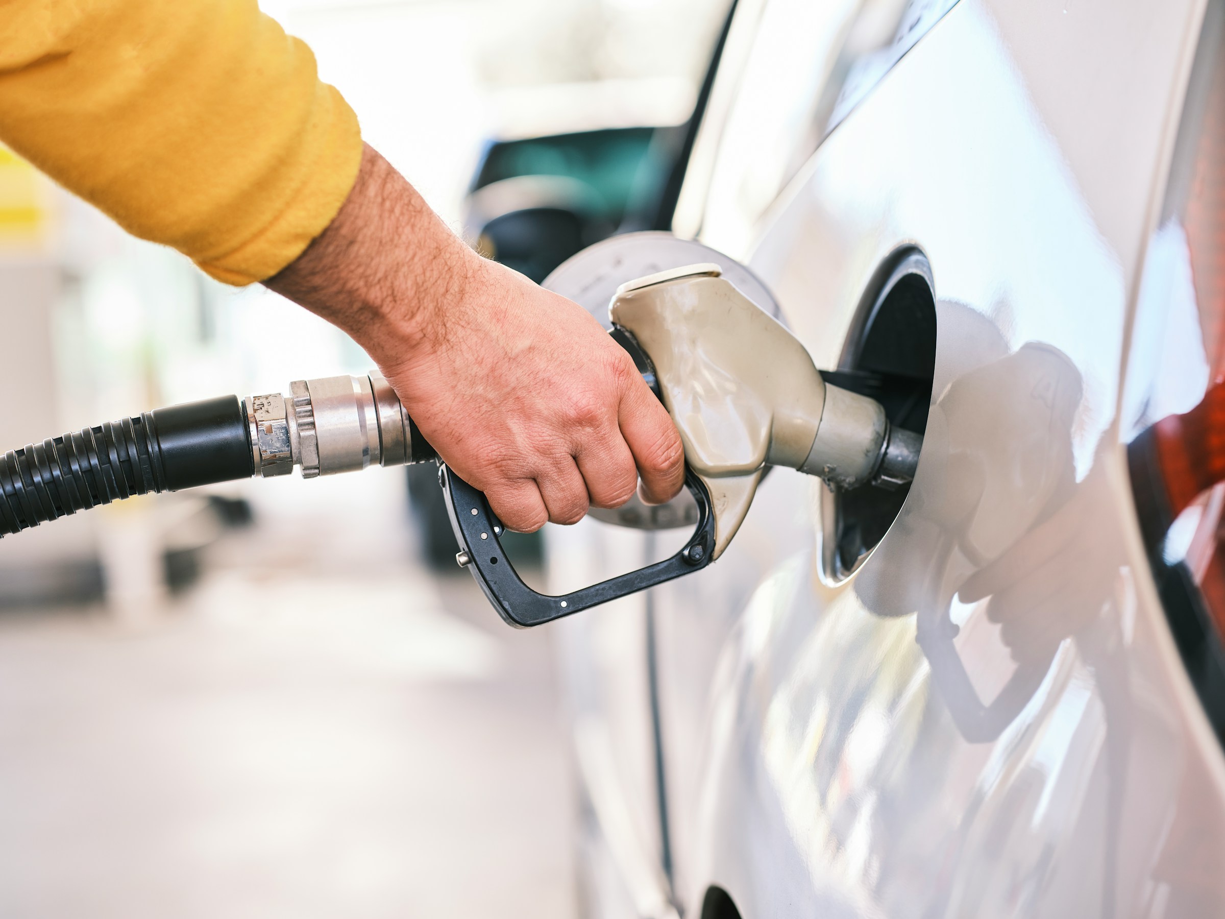 A man in yellow fueling his car on a gas station