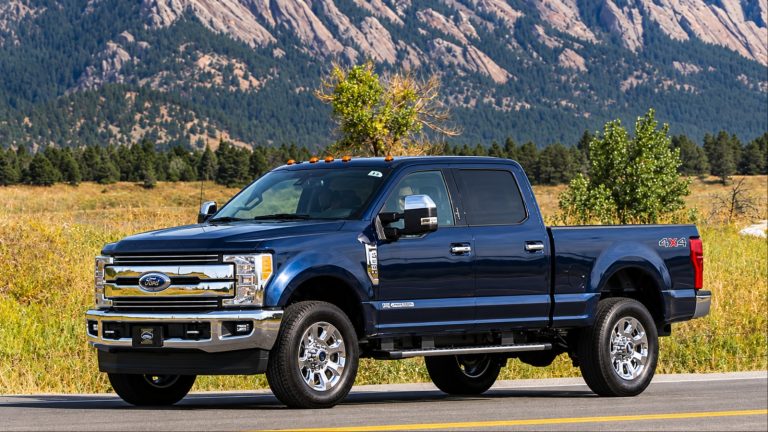 Ford Super Duty pickup driving along a mountain road with rugged peaks behind