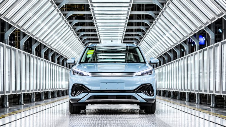 Light blue SUV stands in modern car factory assembly line