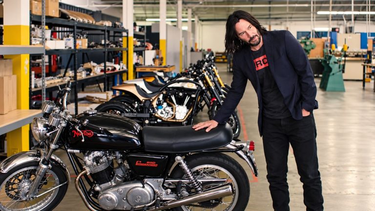 Keanu Reeves examines a classic Norton motorcycle inside his extensive motorcycle workshop collection