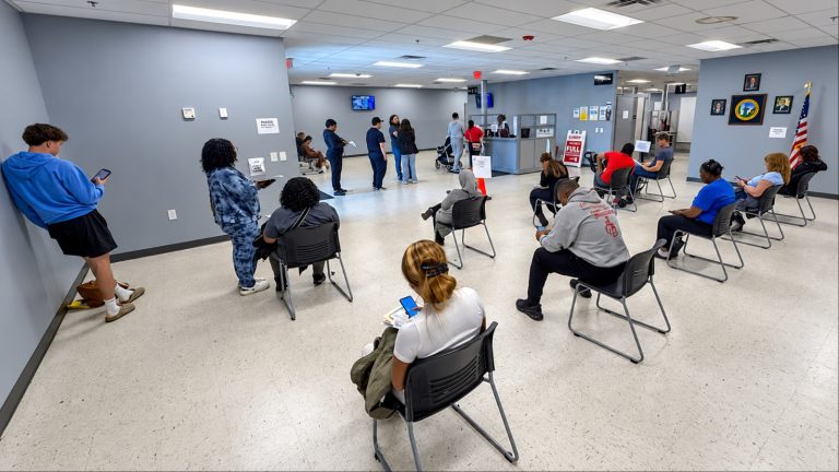 People waiting in chairs at busy DMV office interior