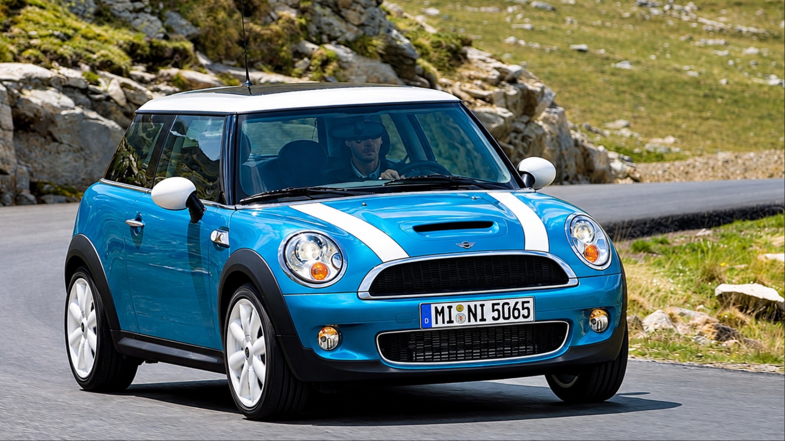 Mini Cooper is cruising on a hilly road on a sunny day
