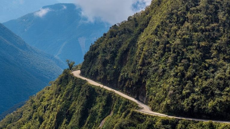 Narrow winding dirt road carved into a steep green mountain