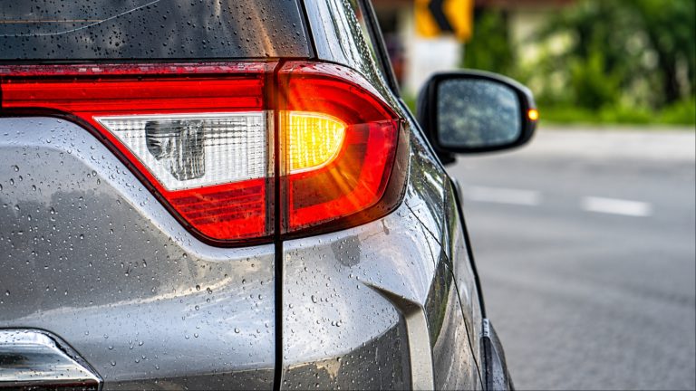 Rain droplets cover a car’s taillight as its turn signal illuminates