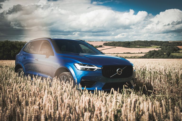 A blue Volvo is cruising slowly on a wheat land