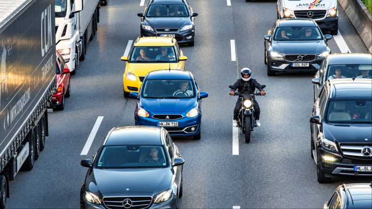 Dense highway traffic with cars trucks and a motorcyclist