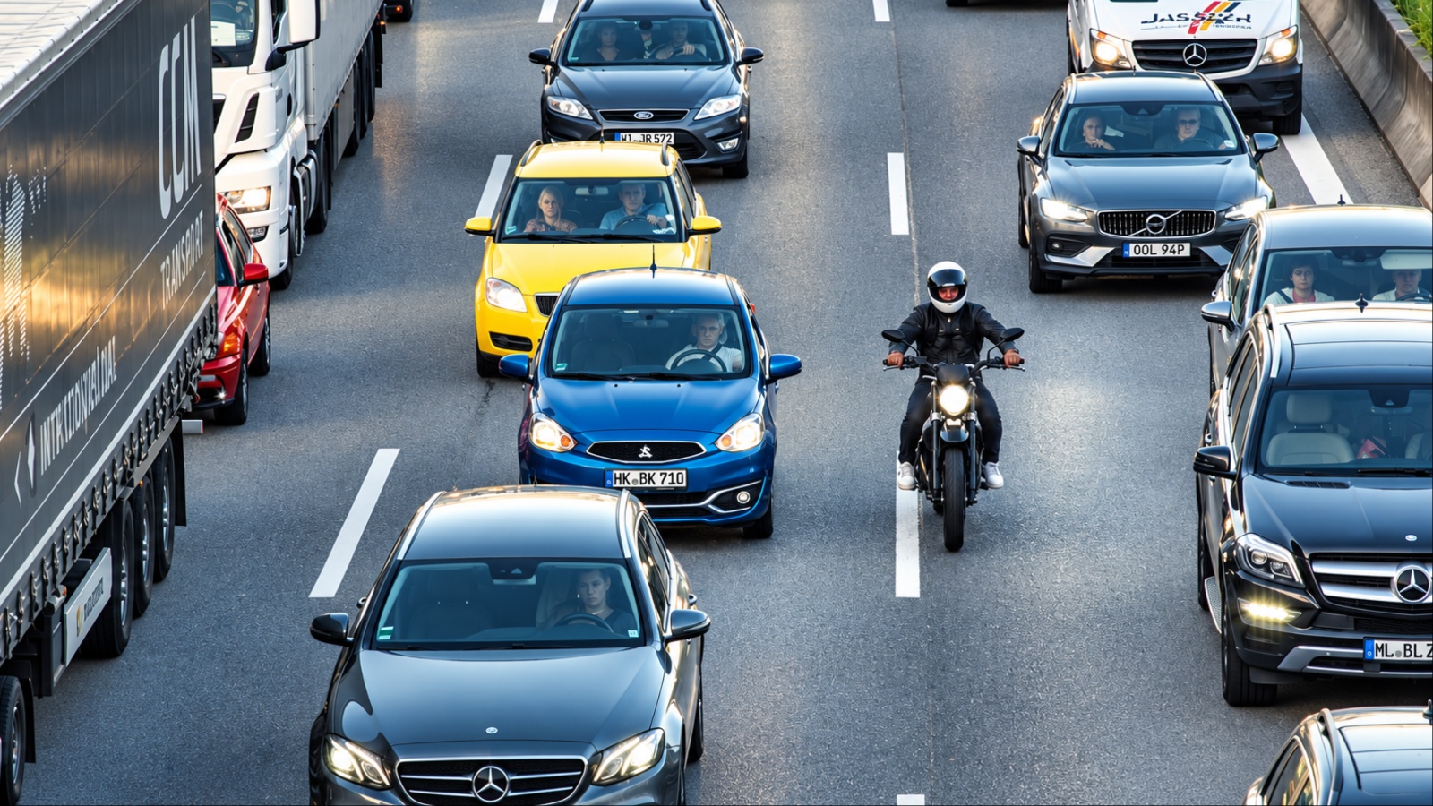 Dense highway traffic with cars trucks and a motorcyclist
