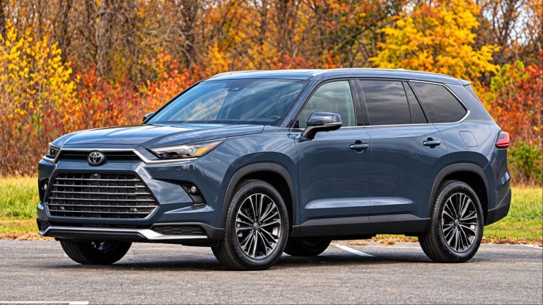 Toyota Grand Highlander Hybrid parked on a road surrounded by autumn foliage