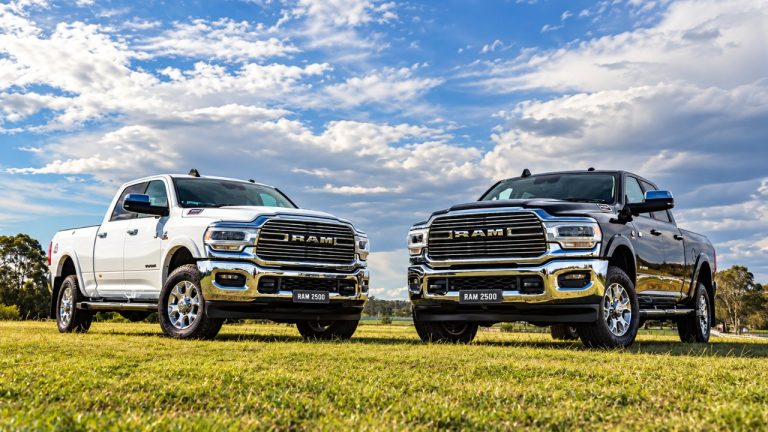 Two heavy-duty RAM 2500 pickups parked side by side on a grassy field