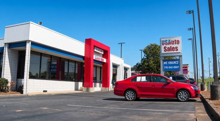 Used car dealership displays a red sedan outside its sales and financing showroom