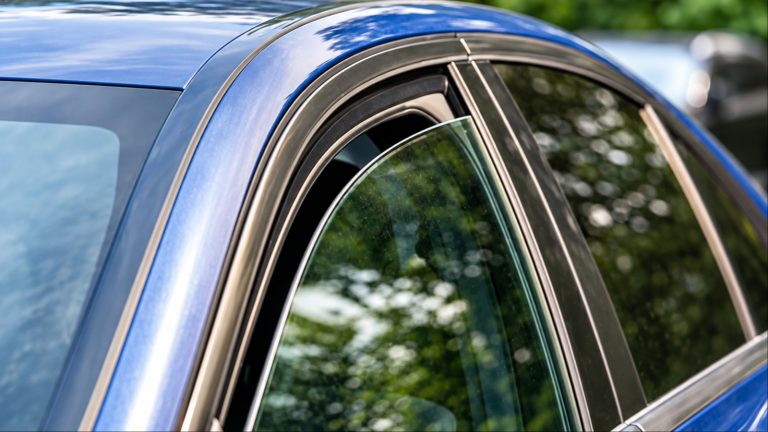 Close-up of blue car window with chrome trim outdoors